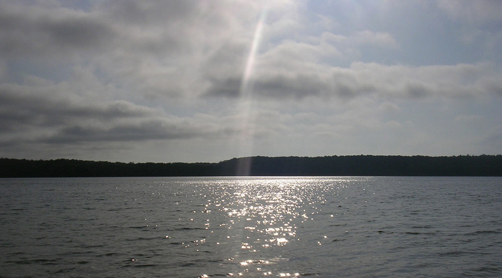 The sun reflects off of Cliff Pond in Brewster, one of the best trout fishing ponds on Cape Cod.