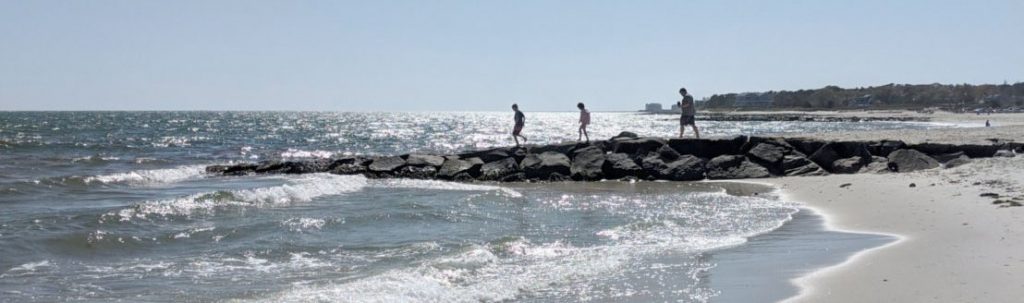 A family walking a jetty at Red River Beach in Harwich, Cape Cod.