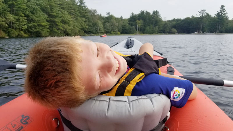 A boy smiling while kayaing in Bourne, Massachusetts.