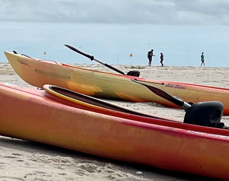 Two Kayaks rest on the beach.
