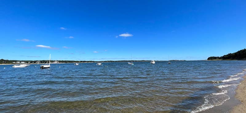 Sipson Island is visible in the distant horizon above the dark blue boat on the far right in this photo as seen from Jackknife Beach in Pleasant Bay.